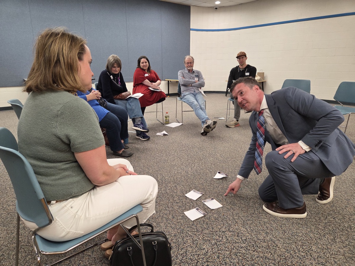 James kneeling to talk with a voter at listening session