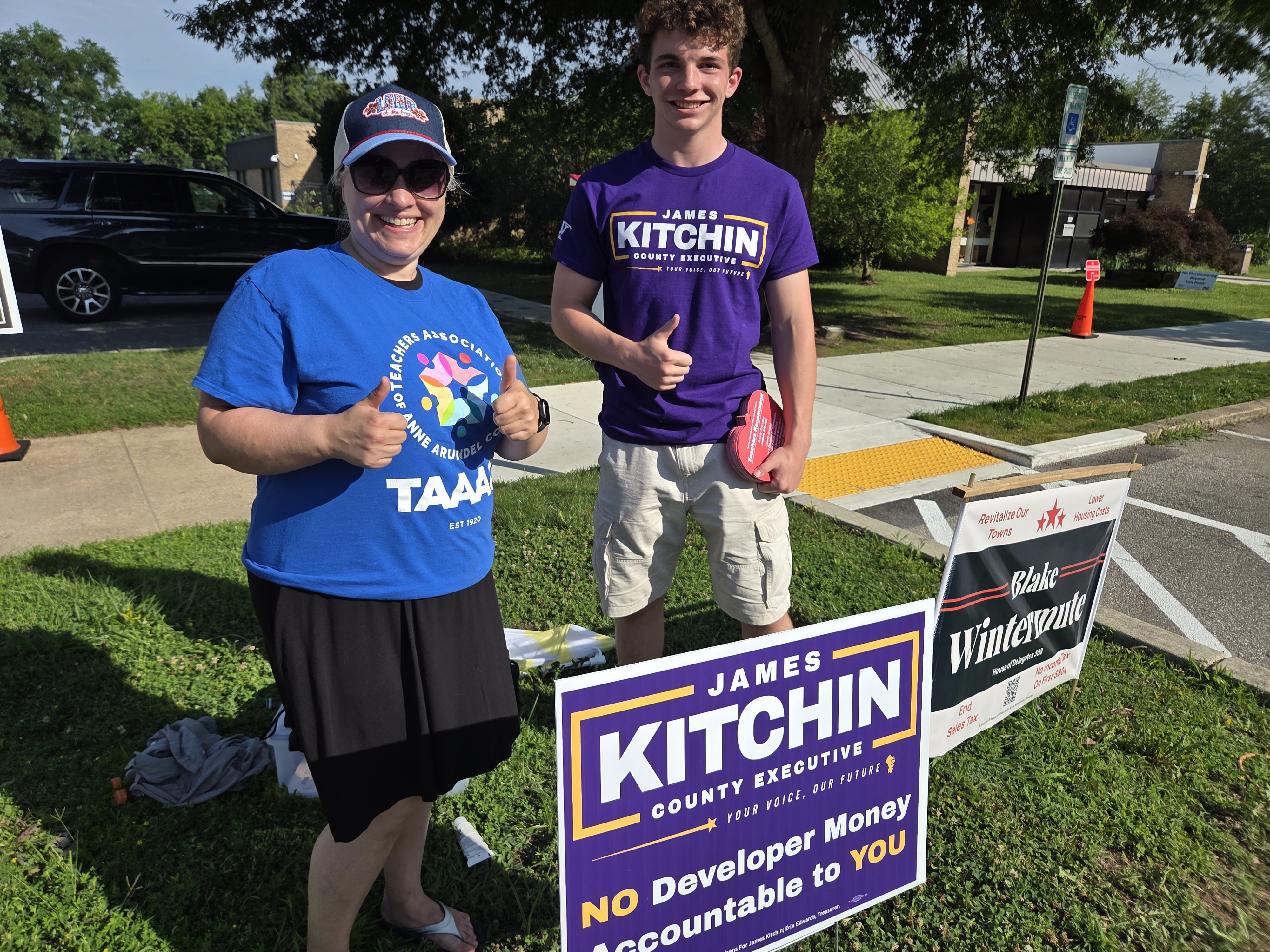 A TAAAC member giving thumbs up with a young canvasser in a Kitchin shirt at the polls